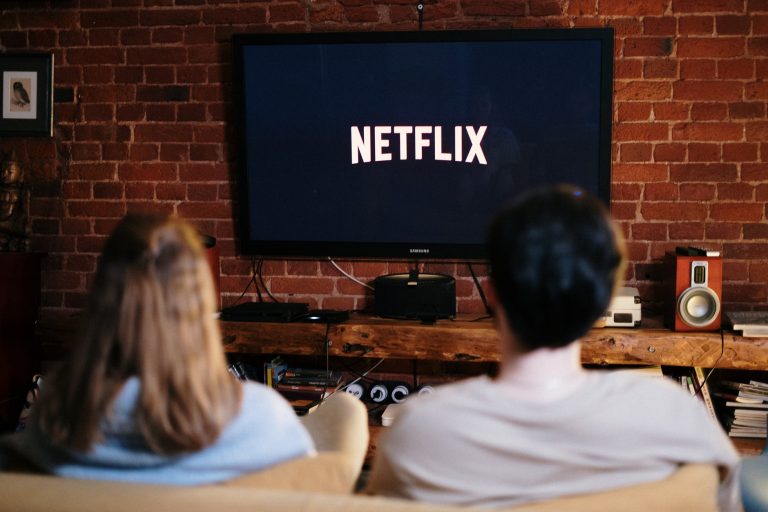 Netflix, man and woman sitting on a couch in front of a television