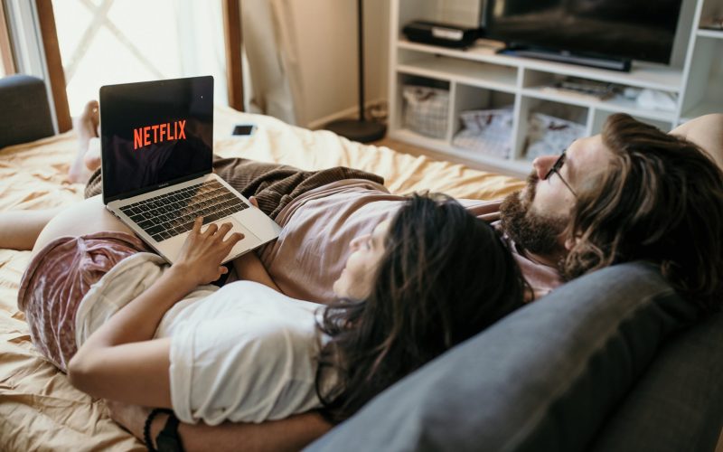 a couple lying in bed watching netflix