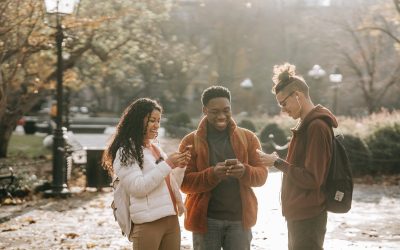 multiracial positive male and female students using smartphones in city park