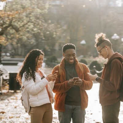 multiracial positive male and female students using smartphones in city park