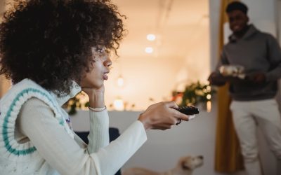 young black woman watching tv with interest near boyfriend standing in room